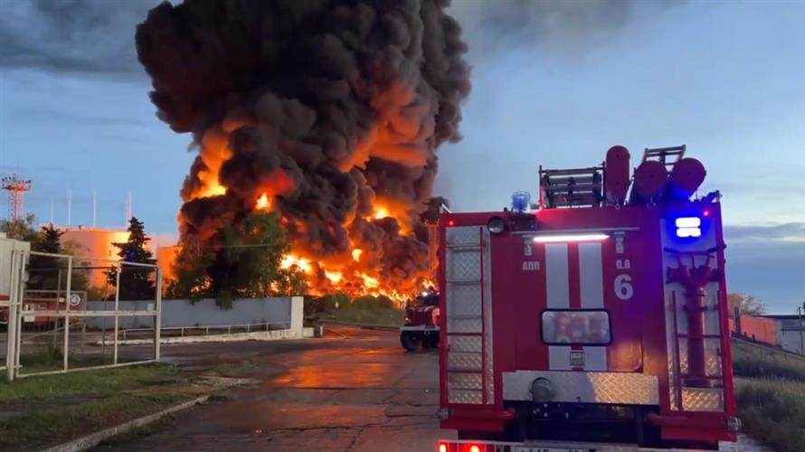 浓烟和火焰从克里米亚储油厂燃烧的油箱中升起，一辆消防车正驶往现场。AP